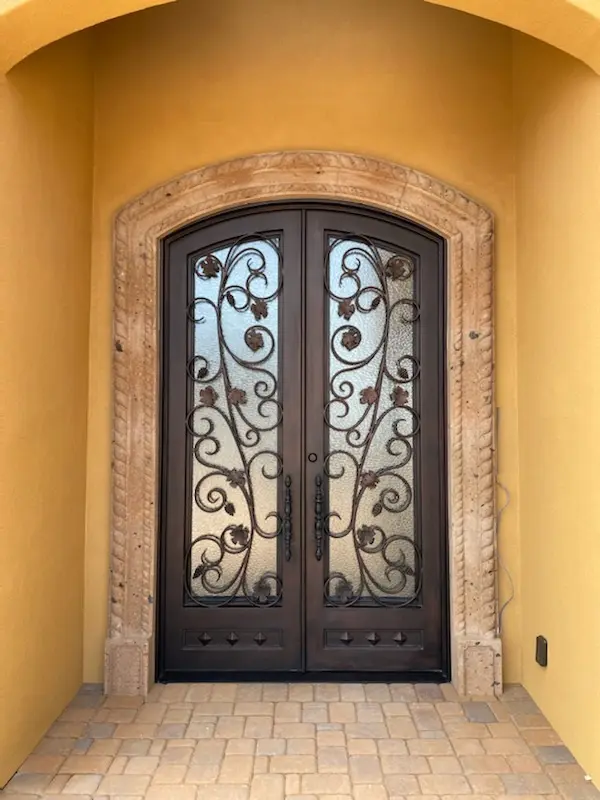 A door with two wrought iron doors and a stone arch.